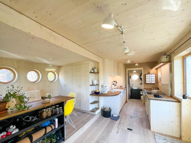 Ein helles, modernes Interieur mit Holzwänden, runden Fenstern und einer offenen Küche.