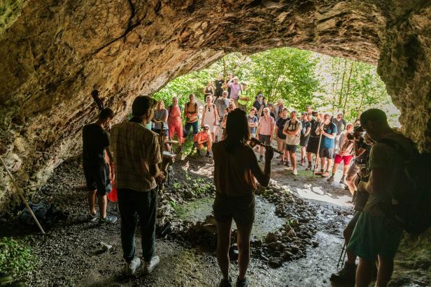 Eine Gruppe von Menschen versammelt sich in einer Höhle, während einige Musikinstrumente spielen.