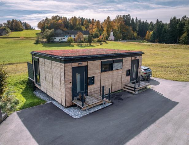 Ein modernes Holzhaus mit Gründach in ländlicher Umgebung.