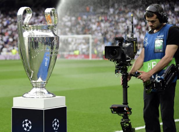 Ein Kameramann filmt den Pokal der UEFA Champions League auf dem Rasen.