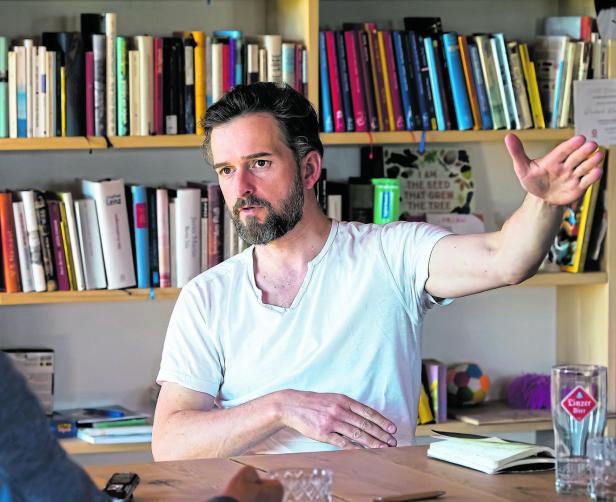 Reinhard Kaiser-Mühlecker gestikuliert während eines Gesprächs vor einem Bücherregal.