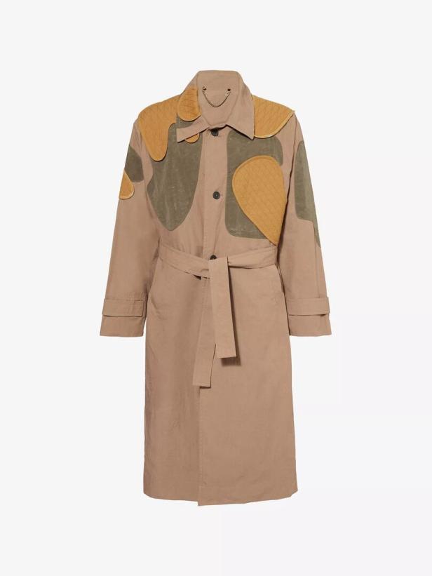 Ein beigefarbener Trenchcoat mit farbigen Applikationen und Gürtel wird gezeigt.