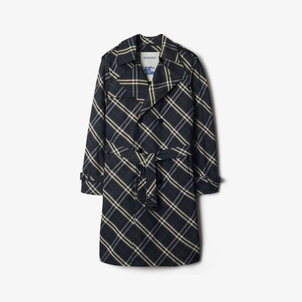 Ein karierter Trenchcoat von Burberry hängt vor einem weißen Hintergrund.