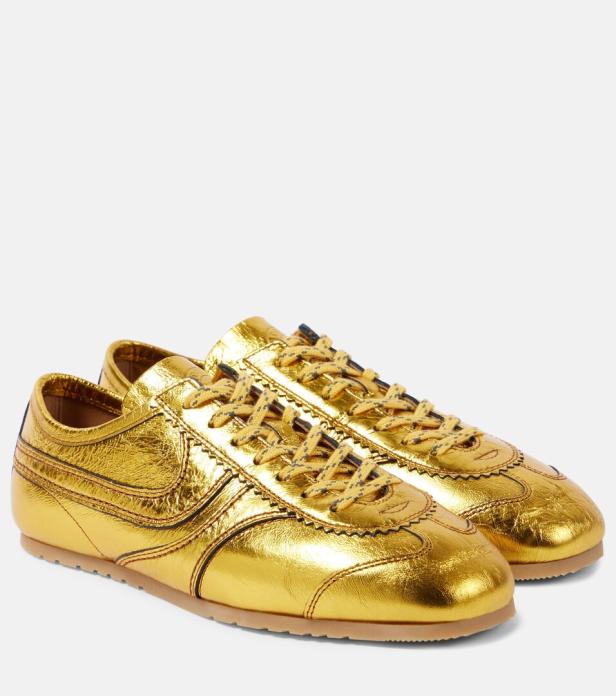 Ein Paar goldene Ledersneakers mit Schnürsenkeln stehen vor einem weißen Hintergrund.