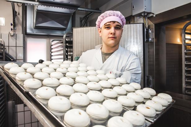 Ein Mitarbeiter in Hygienekleidung präsentiert die Eismarillenknödeln auf einem großen Tablett, bevor sie in den Schockfrostraum kommen.