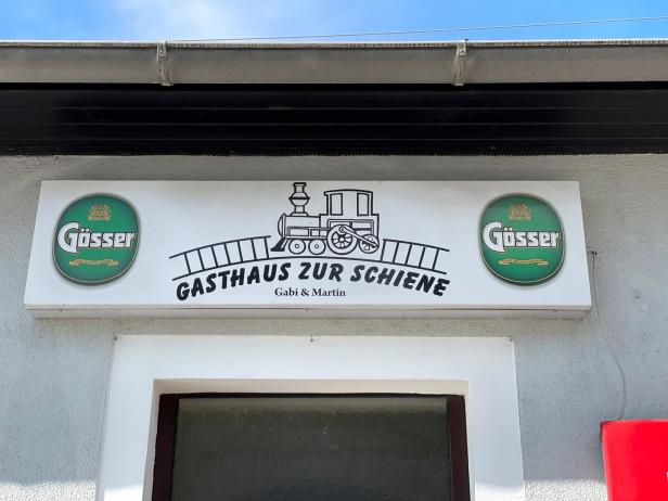 Das Schild für das „Gasthaus zur Schiene“ mit einem stilisierten Zug und Gösser-Logos.