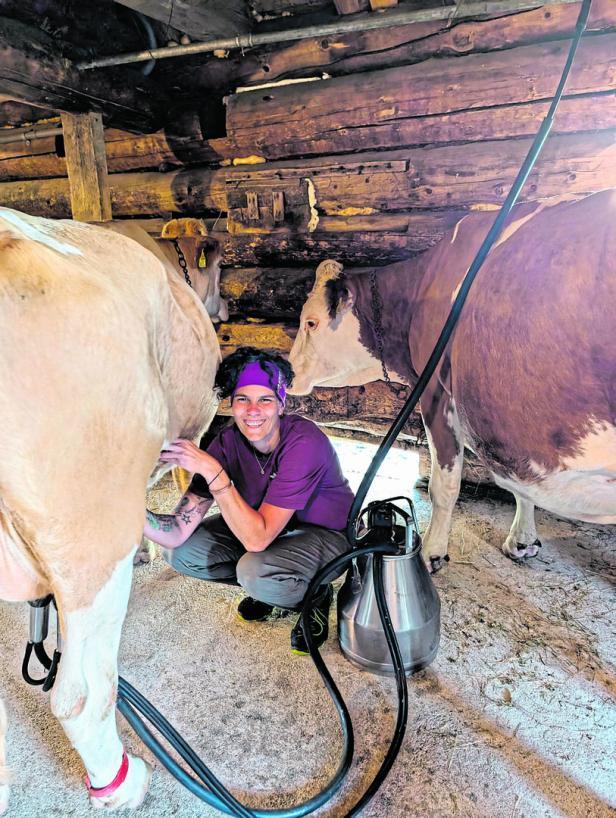 Bernadette Gerauer melkt eine Kuh in einem Stall.