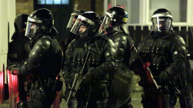 Eine Gruppe Polizisten in voller Schutzausrüstung steht bereit.