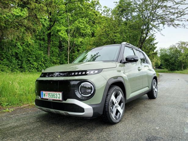 Ein grüner Hyundai Inster steht auf einer nassen Straße.