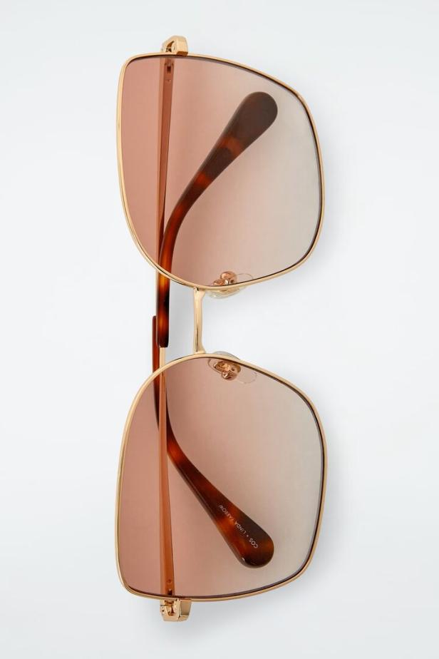 Eine goldfarbene COS x Linda Farrow Sonnenbrille mit braunen Gläsern.
