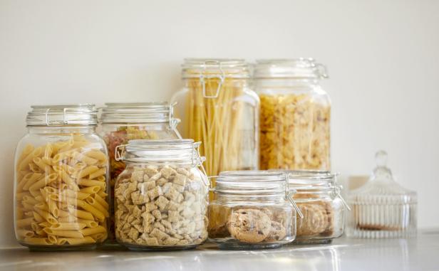 Auf dem Bild sind mehrere Glasbehälter zu sehen, die mit Nudeln, Müsli und Keksen gefüllt sind.