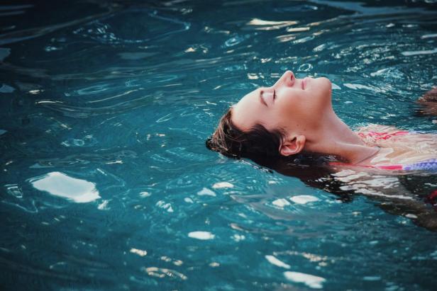Eine Frau lässt sich mit geschlossenen Augen im Wasser treiben. 