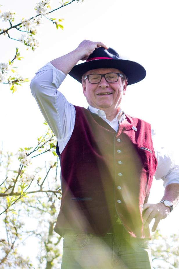 Toni Distelberger mit Trachtenhut vor blühenden Zweigen.