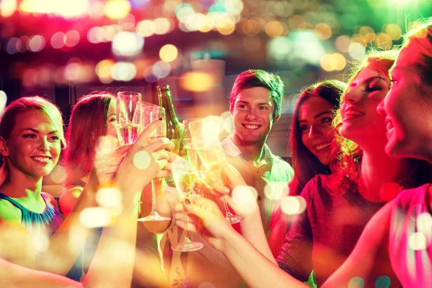 Mehrere Personen prosten sich an einem Tisch auf einer Party zu.