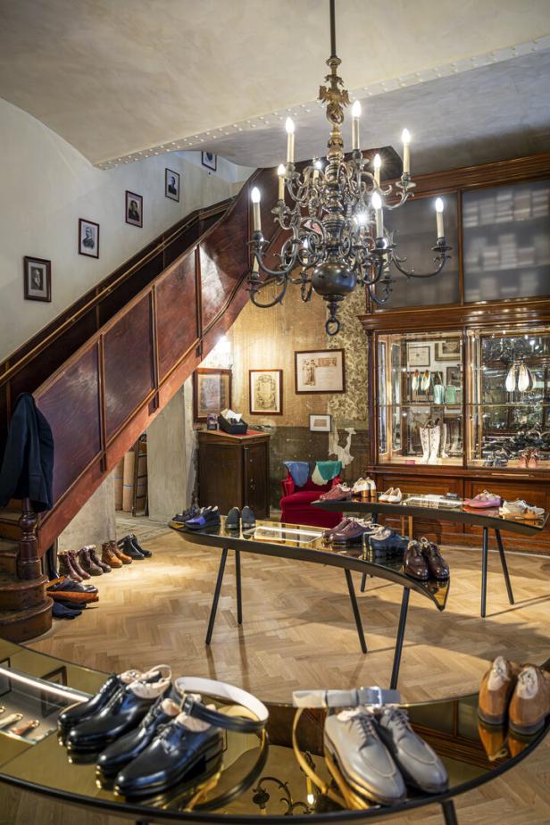 Innenansicht des Schuhgeschäfts Maßschuhe Scheer mit Schuhen auf Tischen und einer Treppe.