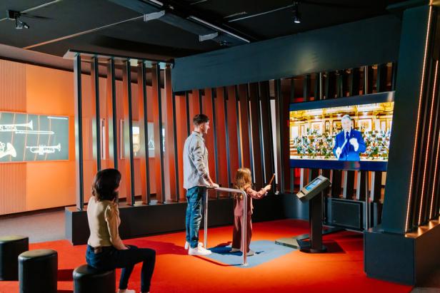 Eine Familie schaut sich ein Video auf einem Fernseher in einer Ausstellung an.