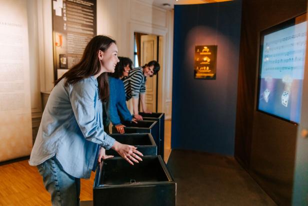 Menschen spielen ein Spiel in einem Museum, umgeben von Ausstellungsstücken und interaktiven Displays.