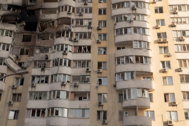 Ein Wohnhaus mit schweren Kriegsschäden, darunter zerstörte Fassaden und zerbrochene Fenster.