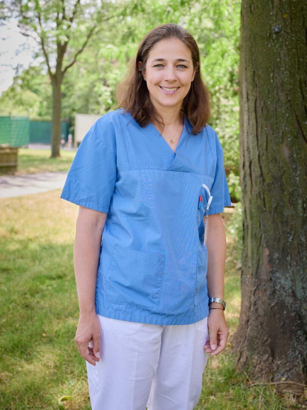 Johanna Brix in Arbeitskleidung steht im Freien vor einem Baum.