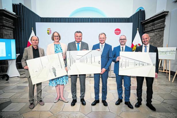 Eine Gruppe von Personen präsentiert Entwürfe für ein Bauprojekt in Oberösterreich.