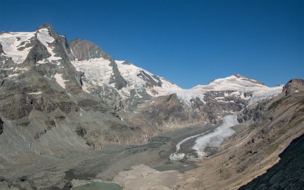 Die schneebedeckten Berge und ein Gletscher unter blauem Himmel.