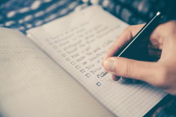 Eine Hand schreibt eine To-Do-Liste.