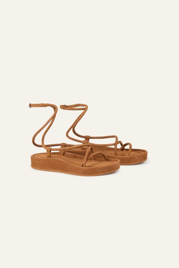 Ein Paar braune Sandalen mit Riemchen auf einem hellen Hintergrund.