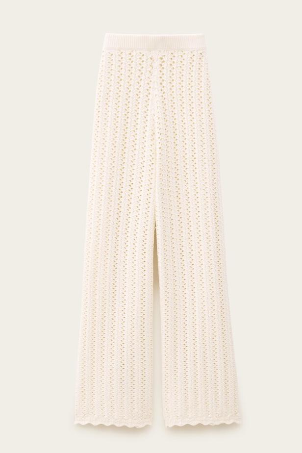 Eine lange, gehäkelte Hose in Cremeweiß vor einem hellen Hintergrund.