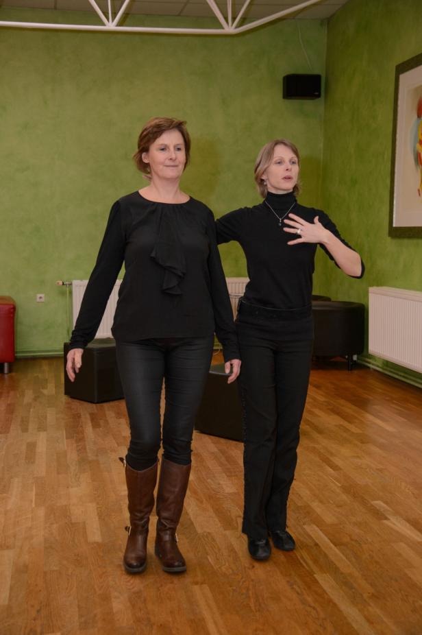 Zwei Frauen in schwarzer Kleidung stehen in einem Tanzstudio.