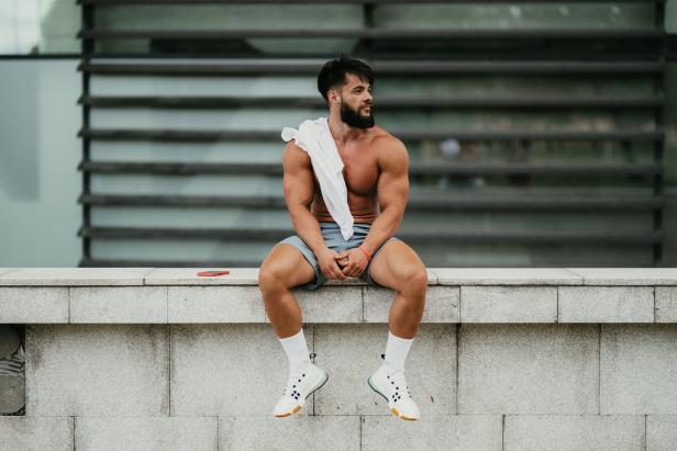 Ein muskulöser Mann entspannt sich nach dem Training im Stadtpark.