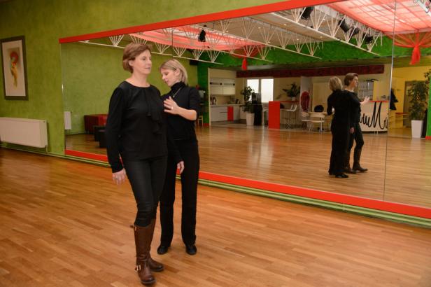Eine Frau erhält Anweisungen von einer Tanzlehrerin in einem Tanzstudio.