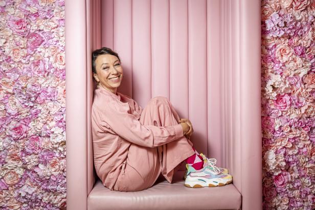 Ursula Strauss sitzt vor einem Hintergrund aus rosa Rosen.