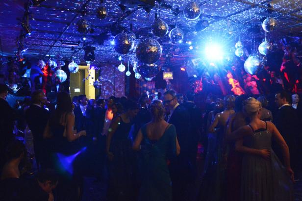 Menschen tanzen unter Discokugeln auf einer Party.