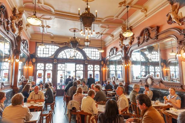 Menschen sitzen in einem verzierten Café an Tischen.