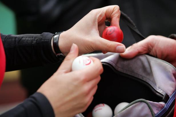 Eine Person nimmt farbige Bälle aus einer Tasche.