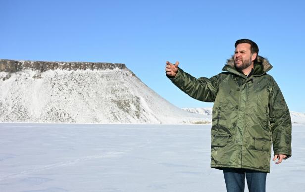 Ein Mann in Winterkleidung steht vor einer verschneiten Landschaft in Island.