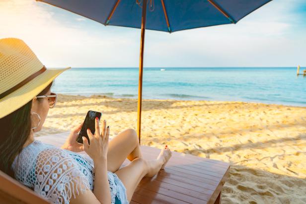 Frau nutzt Smartphone am Strand Frau nutzt Smartphone am Strand
