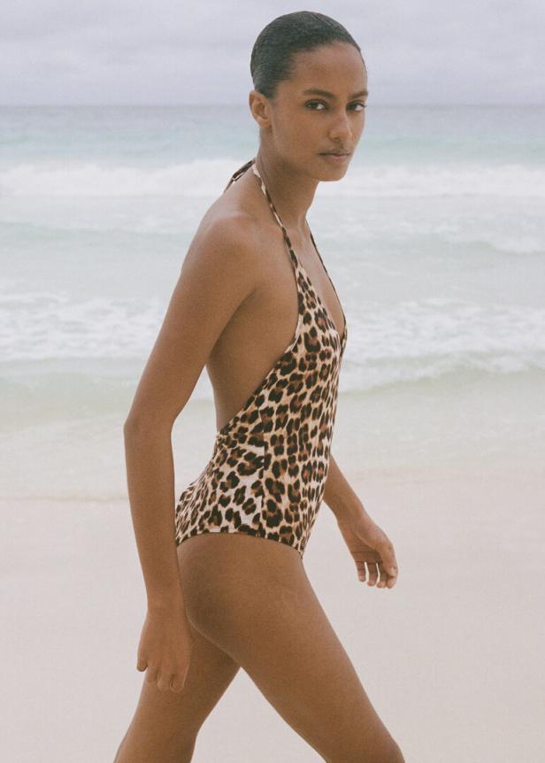 Eine Frau geht am Strand in einem Badeanzug mit Leopardenmuster.
