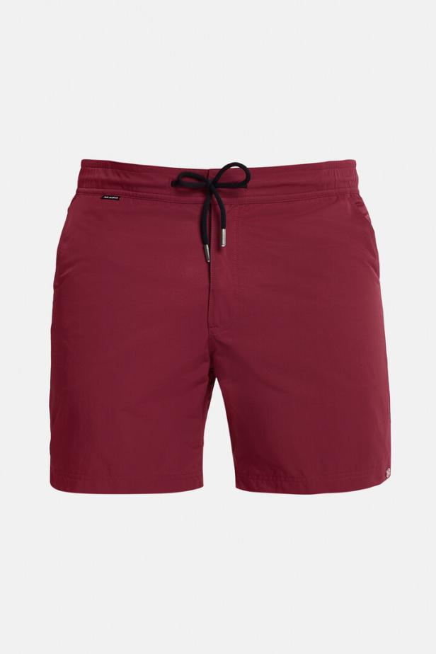 Eine bordeauxrote Badeshorts mit schwarzer Kordel vor einem weißen Hintergrund.