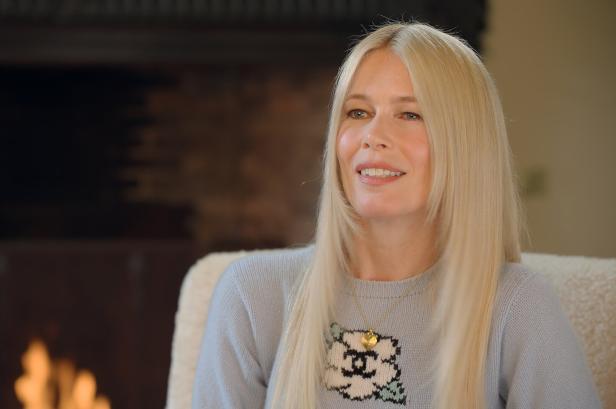 Claudia Schiffer lächelt vor einem Kamin.