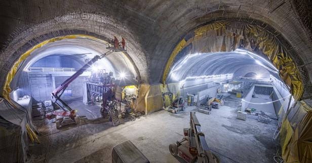 Bauarbeiter arbeiten im Inneren eines großen Tunnelbauprojekts mit schwerem Gerät.