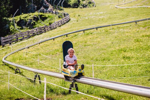 Ein Mädchen benutzt eine Sommerrodelbahn.