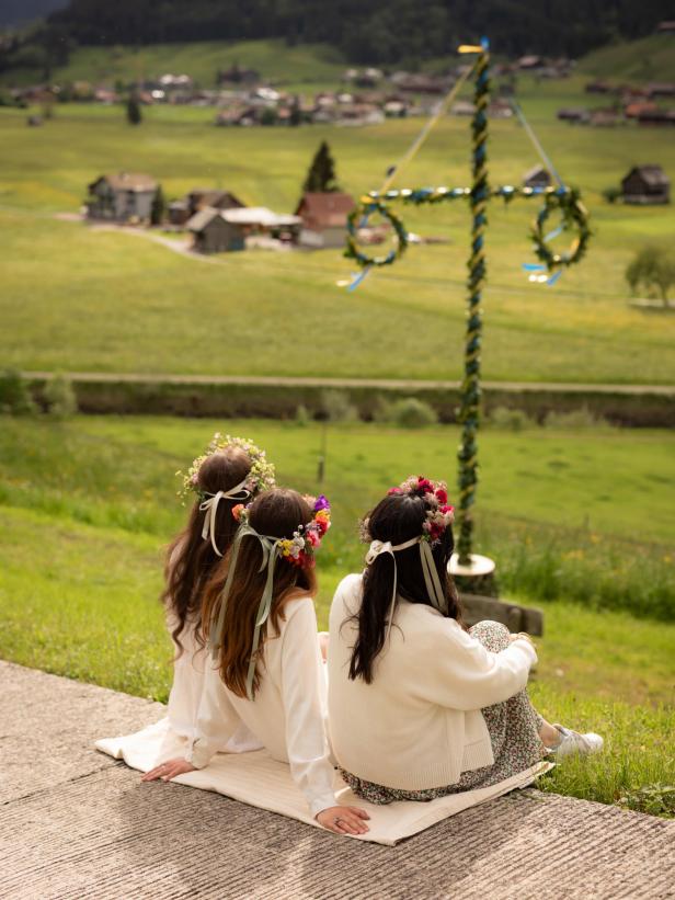 Drei Mädchen mit Blumenkränzen im Haar vor einer Wiese