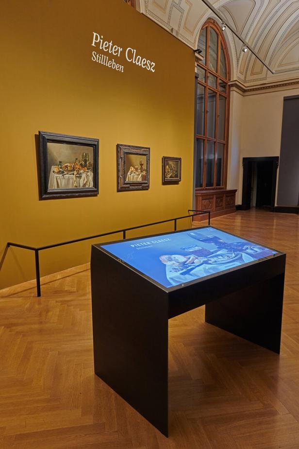 In einem Museum hängen Stillleben von Pieter Claesz an einer gelben Wand.