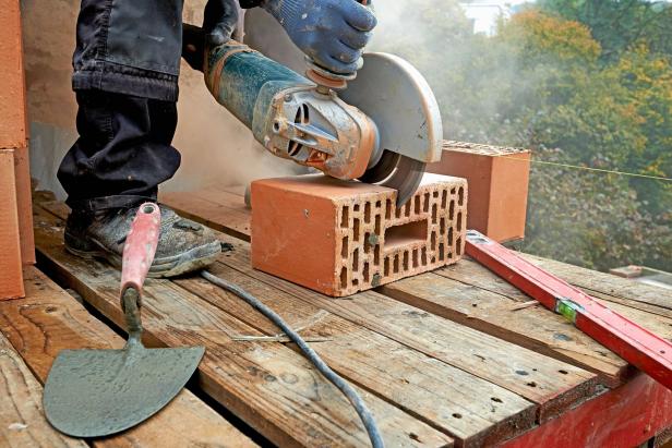 Blue clollar worker cutting concrete block with electric saw