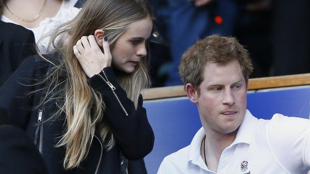 Prinz Harry und eine Frau mit blauen Fingernägeln schauen zu.