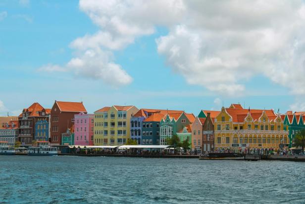 Auf dem Bild sieht man bunte Häuser von Curacao und das Meer.