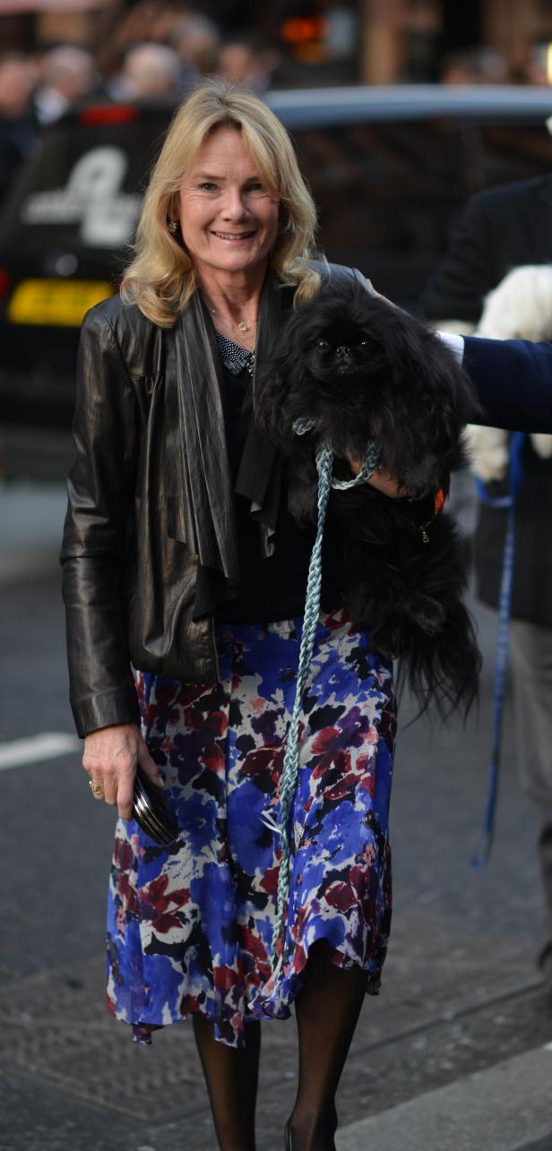 Eine Frau hält einen kleinen schwarzen Hund an der Leine.