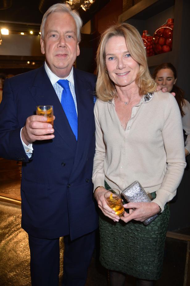 Ein Mann im Anzug und eine Frau mit Cocktailglas posieren für ein Foto.