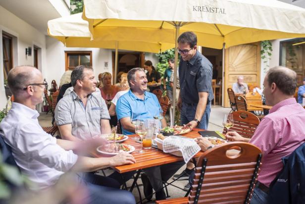 Männer sitzen an einem Tisch und genießen gemeinsam eine Mahlzeit in geselliger Runde.